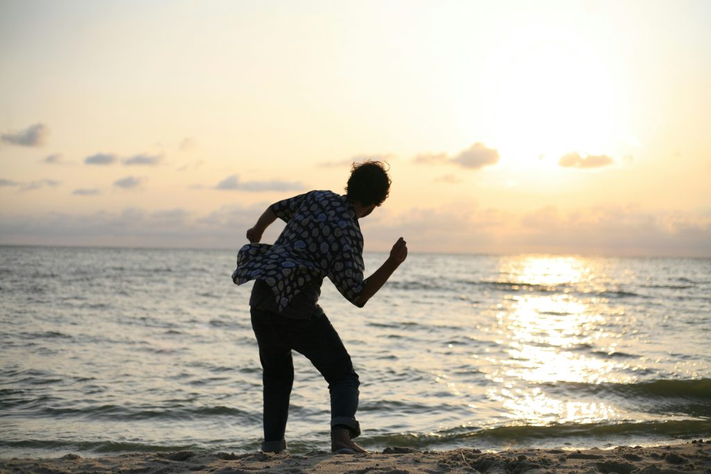 man about to throw stone on sea Skipping stones at sunset