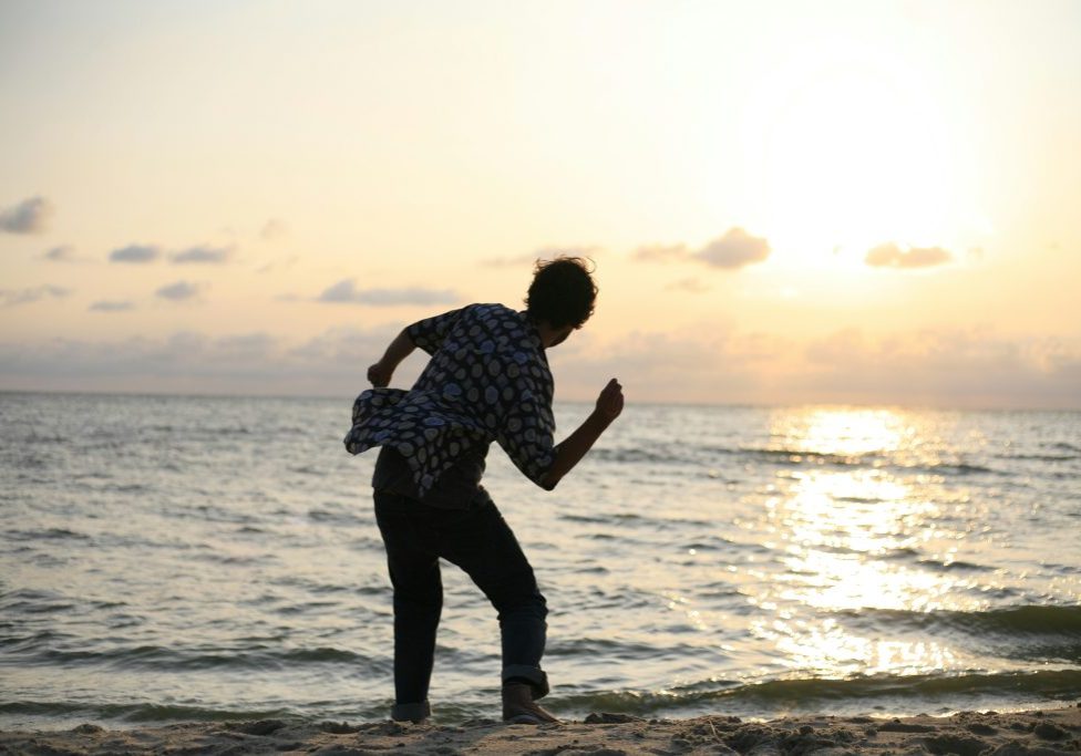 man about to throw stone on sea Skipping stones at sunset